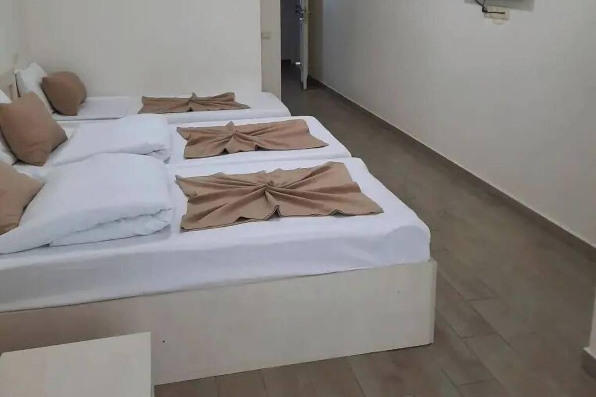 A hotel room with a bed, pillows, a flat-screen TV, and a hallway.