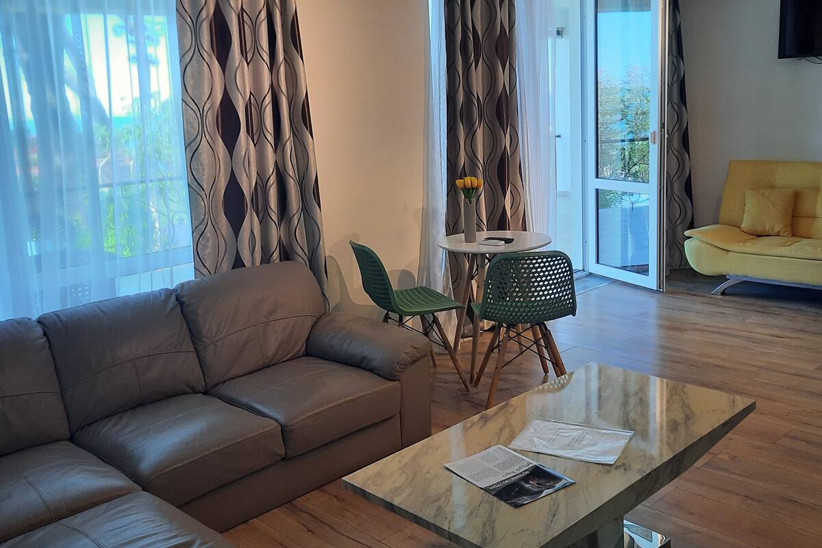 A modern living room with a leather sofa, a glass coffee table, and a green chair.