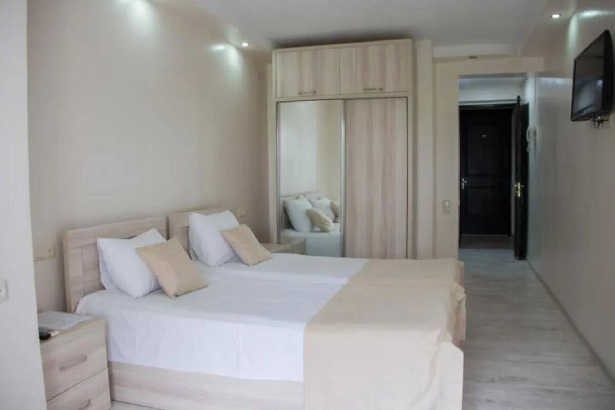 A bedroom with a bed, a wardrobe, a television, and a mirror.