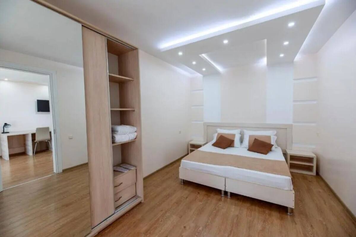 A bedroom with a bed, bedside tables, a wardrobe, and a desk with a chair.