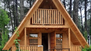 A wooden cabin with a balcony, stone foundation, and a wooden fence. - Kolkhida Resort & Spa (Ureki)