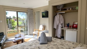 A bedroom with a bed, a desk, a chair, a TV, and a view of the outdoors. - Trout n Trail BnB (Ranfurly)