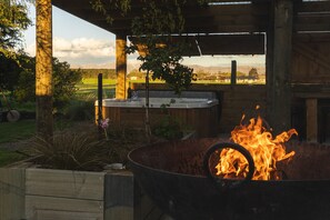 An outdoor kitchen area with a fire pit, a sink, and a view of a vineyard and mountains.
