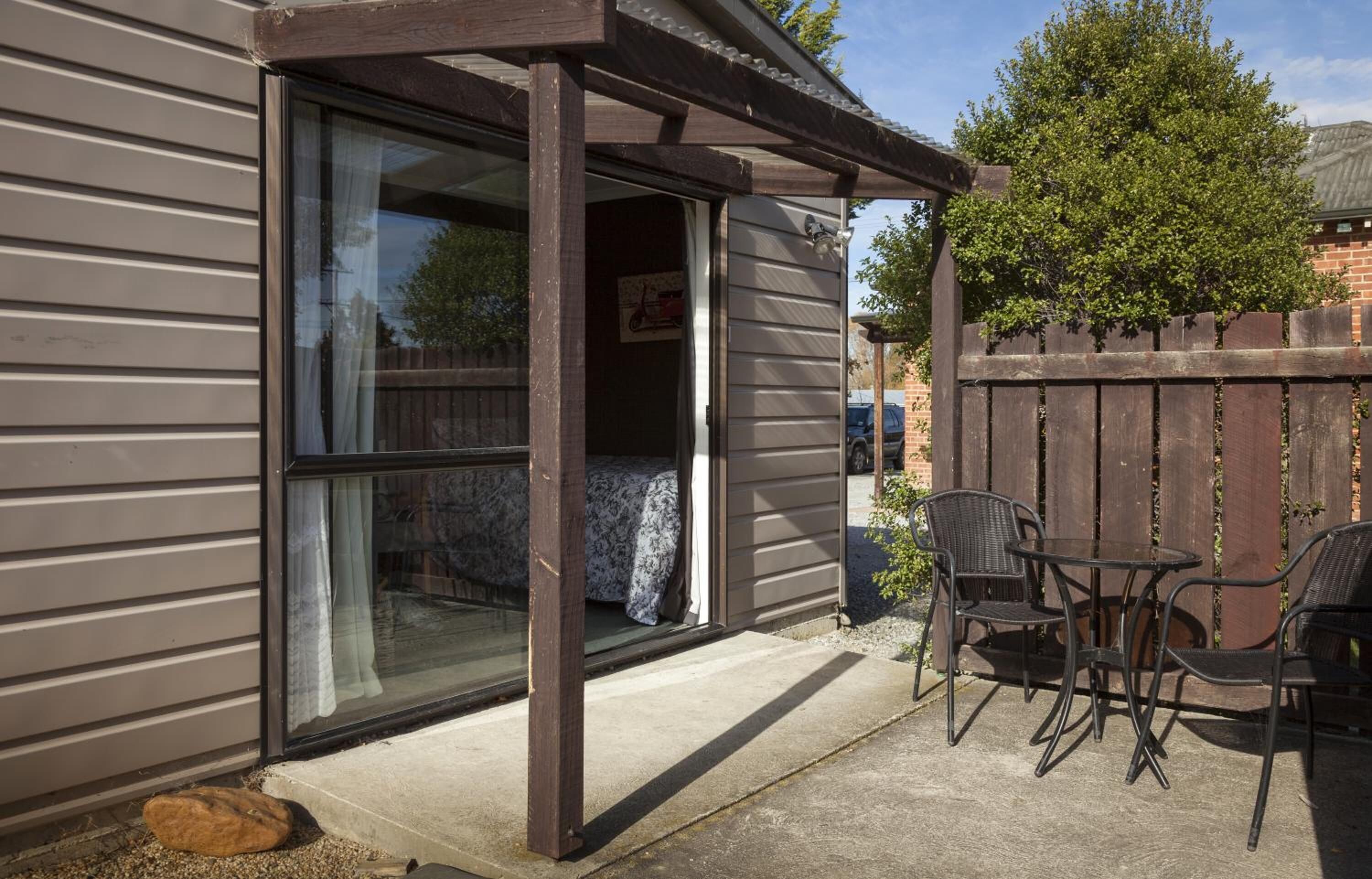 A patio with a sliding glass door leading to a room, a wooden fence, and outdoor furniture.