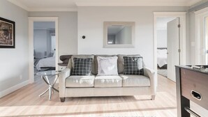 A modern living room with a light-colored sofa, a small glass table, and a mirror on the wall. - Ocean-view 5BR near SF — sleeps 25 (Pacifica)