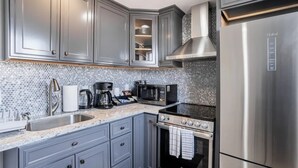 A modern kitchen with grey cabinets, a stainless steel refrigerator, a built-in oven, and a coffee maker. - Private Pacifica suite near the beach (Pacifica)