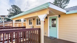 A covered deck with a wooden railing, a light green door, and a small porch area with a bench. - Private Pacifica suite near the beach (Pacifica)