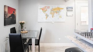 A modern dining area with a glass table, black chairs, a world map on the wall, and a painting of a cityscape. - Private Pacifica suite near the beach (Pacifica)