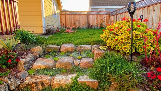 A backyard with a stone pathway, a wooden fence, and a variety of plants and flowers. - Private Pacifica suite near the beach (Pacifica)
