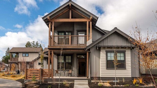 A two-story house with a balcony, a front porch, and a garage. - Bluebird Day - Wild River Getaway, Escape to this cozy 2-bedroom retreat in Bend, OR. (Bend)