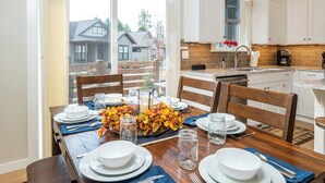 A dining area with a wooden table set for four, white plates, and clear glasses. - Bluebird Day - Wild River Getaway, Escape to this cozy 2-bedroom retreat in Bend, OR. (Bend)