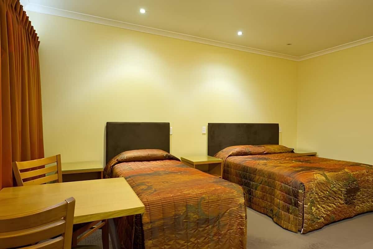 Une chambre d’hôtel avec deux lits simples, une table en bois et une chaise.