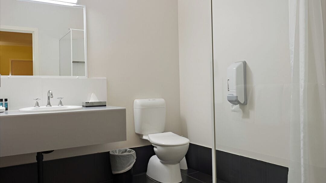 A modern bathroom with a white sink, a toilet, and a hand dryer.
