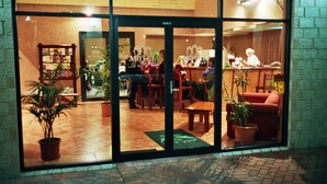 A restaurant with a tiled floor, wooden furniture, and potted plants. - Motel Le Grande (Orana)