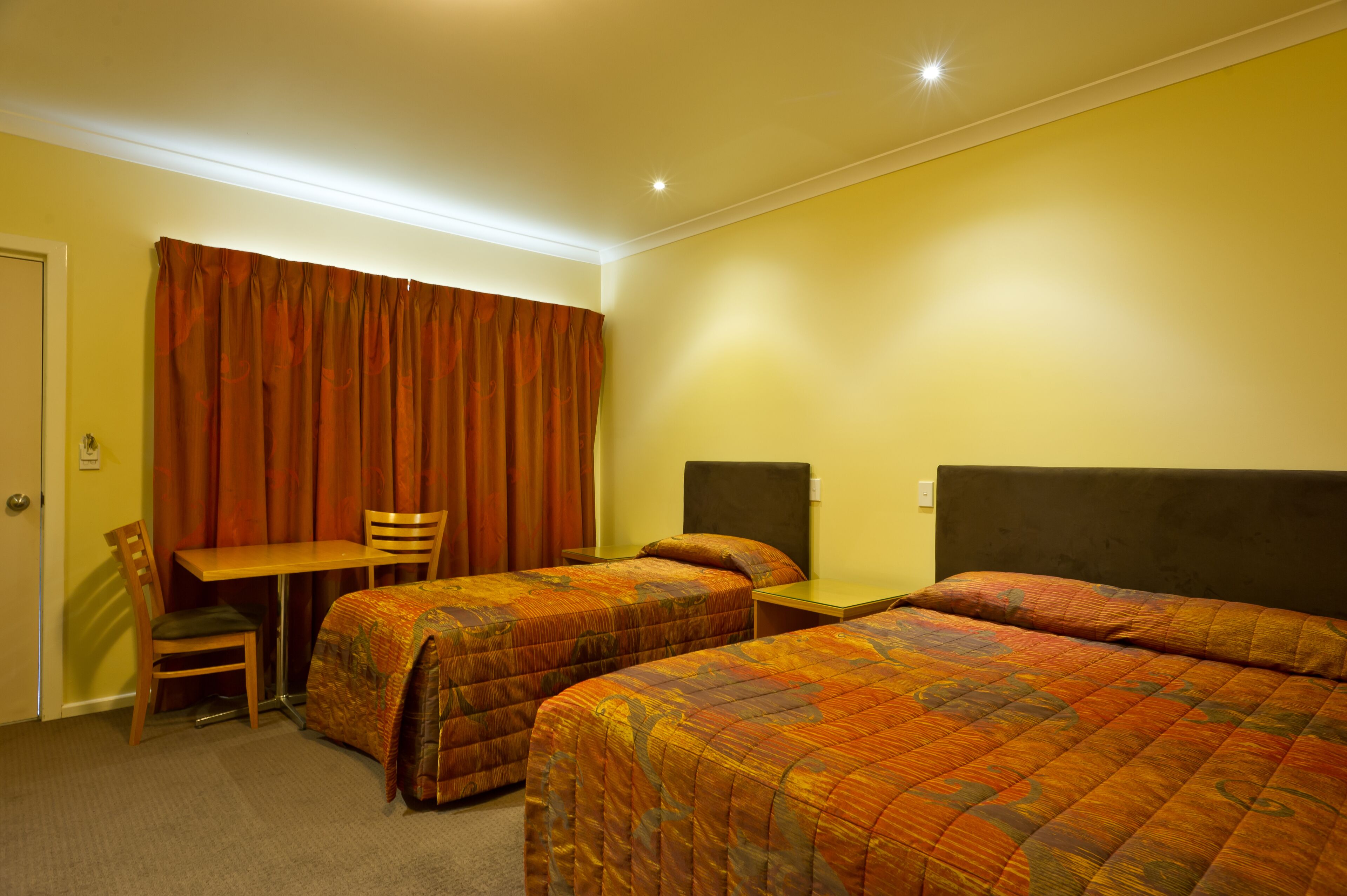 Ein Hotelzimmer mit zwei Betten, einem Schreibtisch und einem Stuhl.