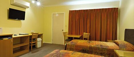 A hotel room with two beds, a desk, a chair, a television, and a wardrobe.
