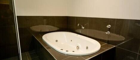 A bathroom with a large freestanding bathtub, a smaller sink, and a mirror.