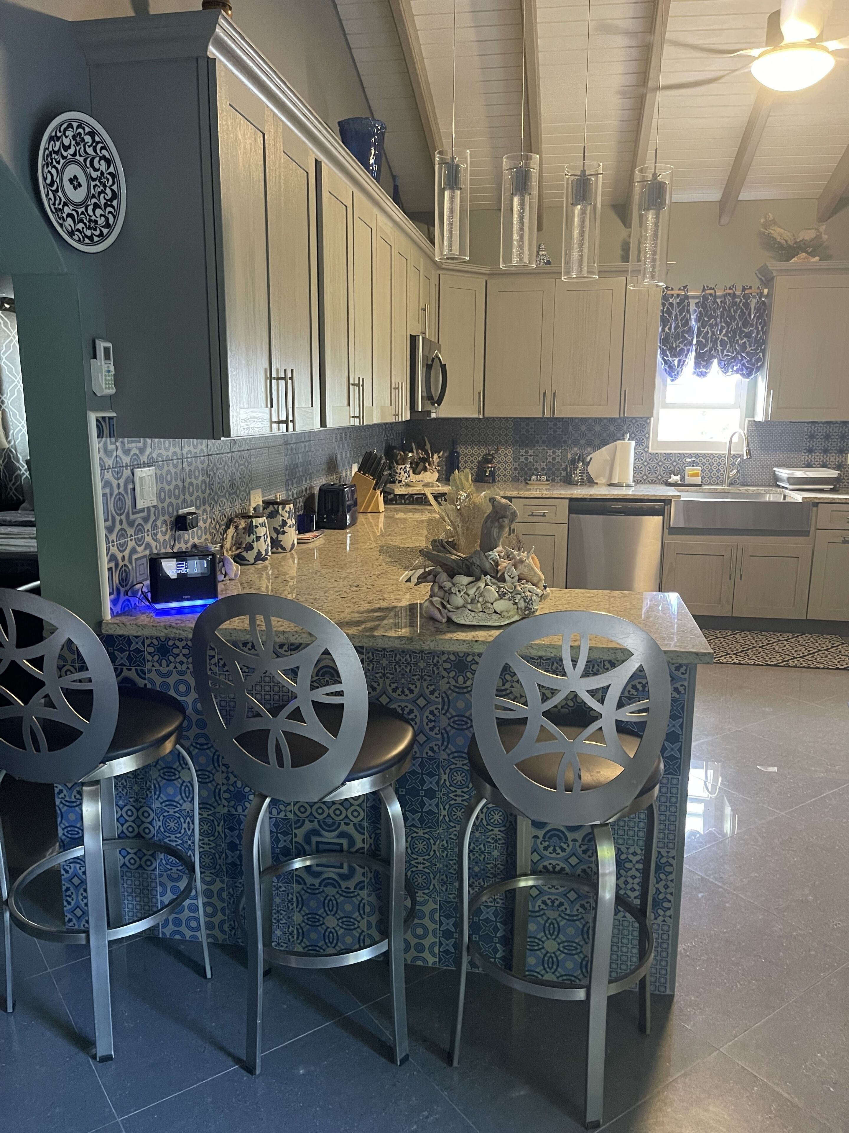 A modern kitchen with a central island, bar stools, and a built-in oven.