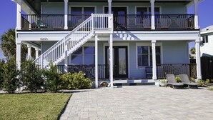 Une maison à deux étages avec un balcon, un escalier et une véranda à l’avant.