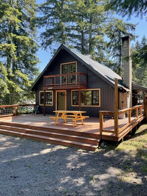 Eine Holzhütte mit einer Holzterrasse, einem Picknicktisch und einem Schornstein.