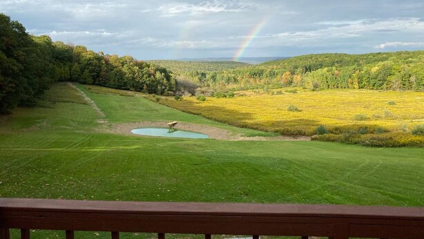 A grassy field with a pond, a rainbow, and a forested hill in the background. - Stargazer-Magnificent Picturesque View-Dark Skies-Hiking-Biking-Wildlife-Pets (Wellsville)