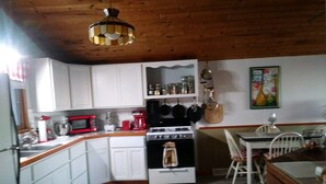 A kitchen with white cabinets, a stove, a microwave, and a hanging pot rack. - Stargazer-Magnificent Picturesque View-Dark Skies-Hiking-Biking-Wildlife-Pets (Wellsville)