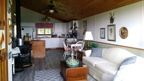 A cozy living room with a fireplace, a dining area, and a kitchen with wooden beams. - Stargazer-Magnificent Picturesque View-Dark Skies-Hiking-Biking-Wildlife-Pets (Wellsville)