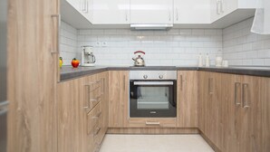 Una cocina moderna con armarios de madera, horno empotrado y salpicadero de azulejos blancos.
