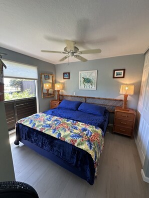 A bedroom with a bed, two bedside lamps, a ceiling fan, and a window with blinds. - #05 Colony One at Sea Mt. Punalu`u (Pahala)