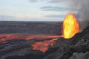Un paysage volcanique où la lave coule et où une importante éruption est en cours.
