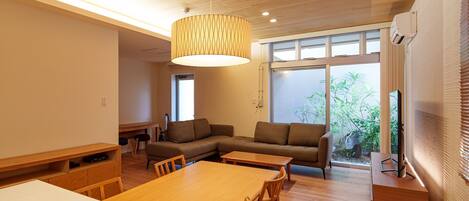 Una sala moderna con una mesa de comedor de madera, sofá y un ventanal con vistas a zonas verdes.