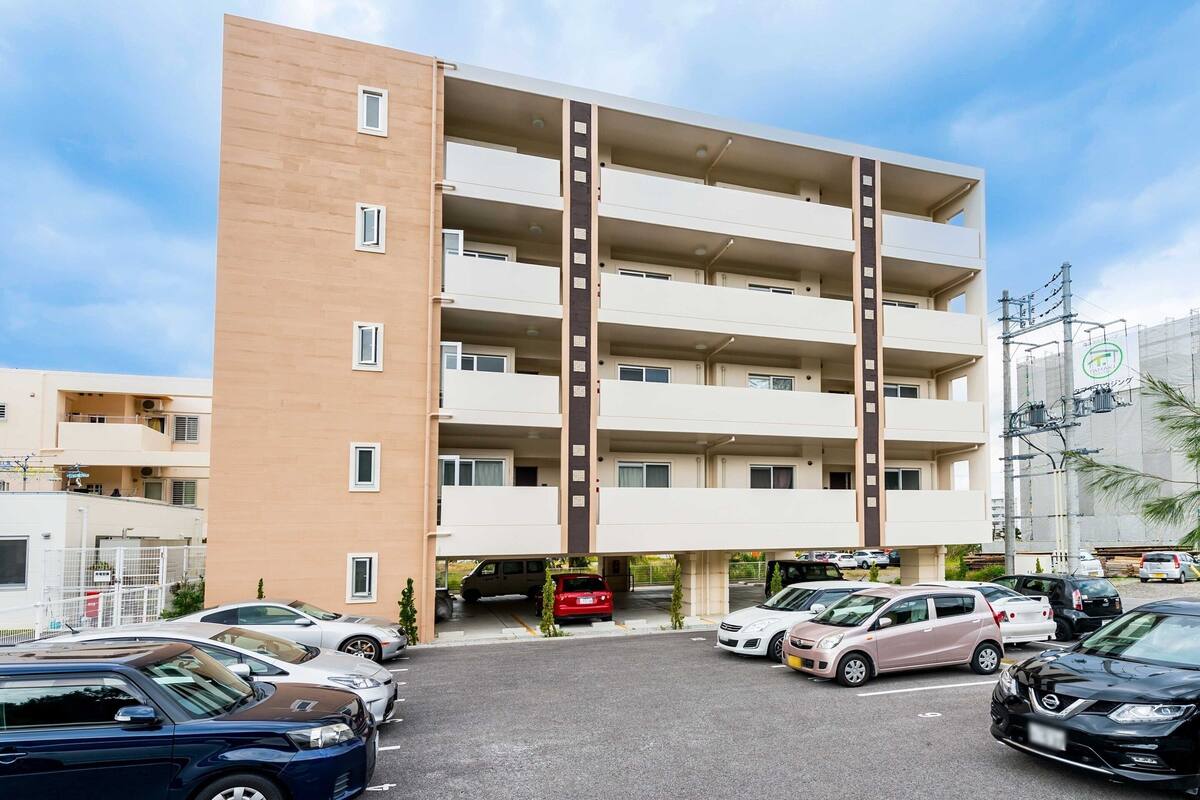 A multi-story residential building with a parking area in front.