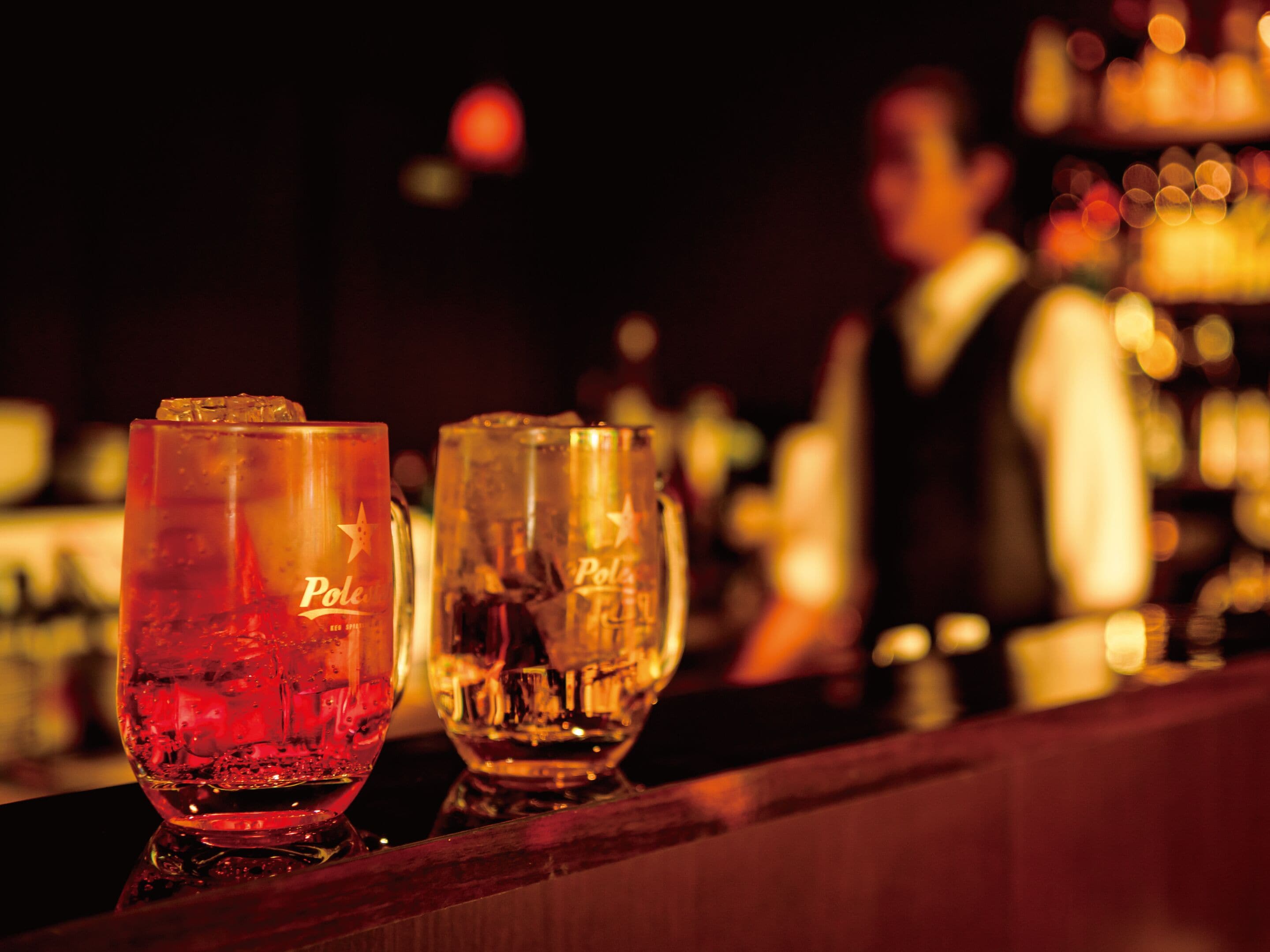 Dos vasos con la palabra "Poles" escritos, sobre una barra de bar.