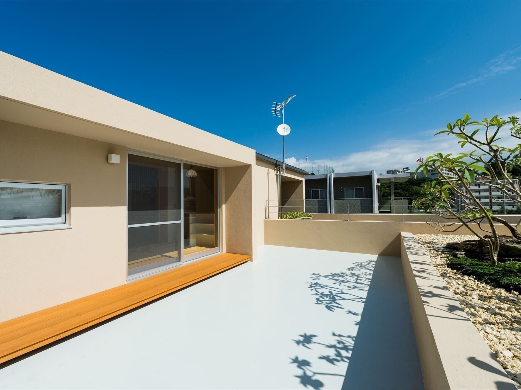 A modern building with large windows, a wooden deck, and a satellite dish.