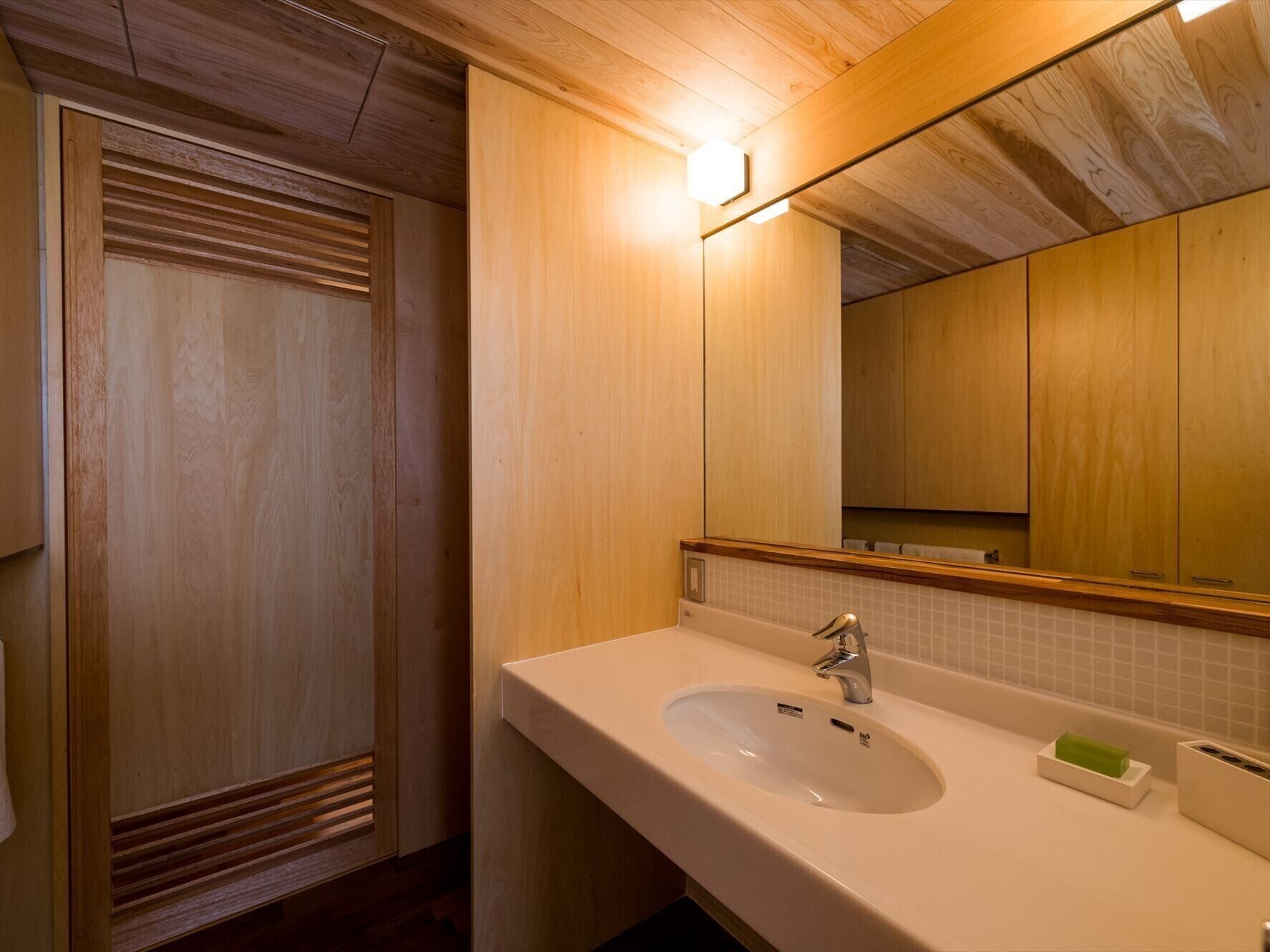 Een badkamer met een houten wastafelmeubel, een wastafel, een spiegel en een handdoekrek.