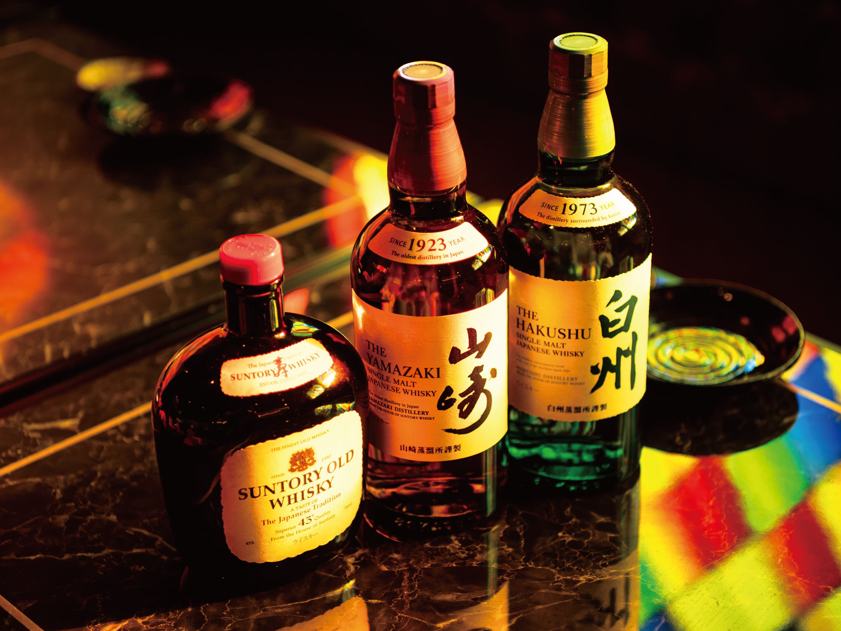 Three bottles of whisky on a reflective surface.