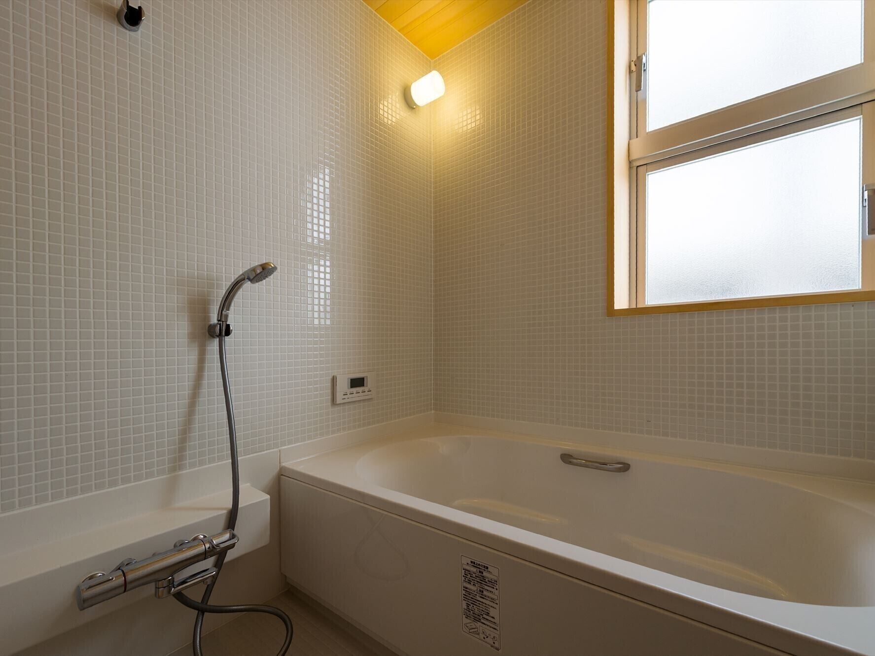 A bathroom with a bathtub, a shower head, and a window.