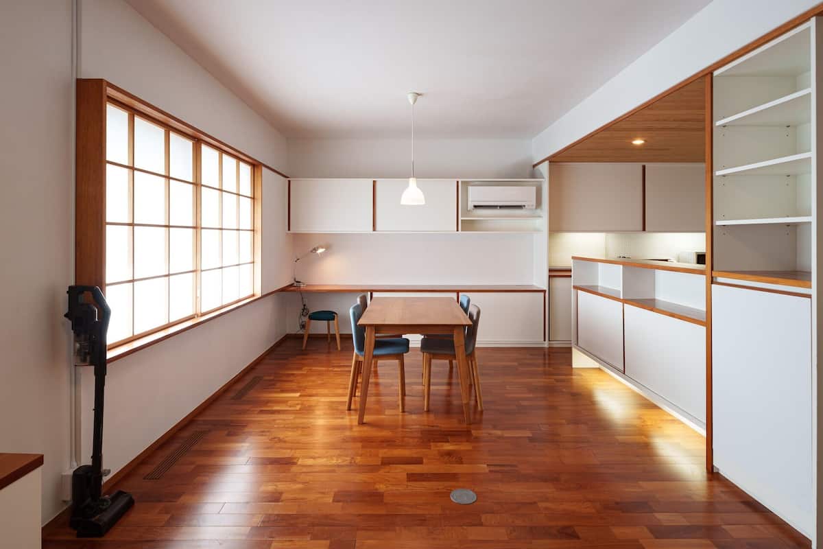 A compact kitchen with a dining table, chairs, and a built-in oven.