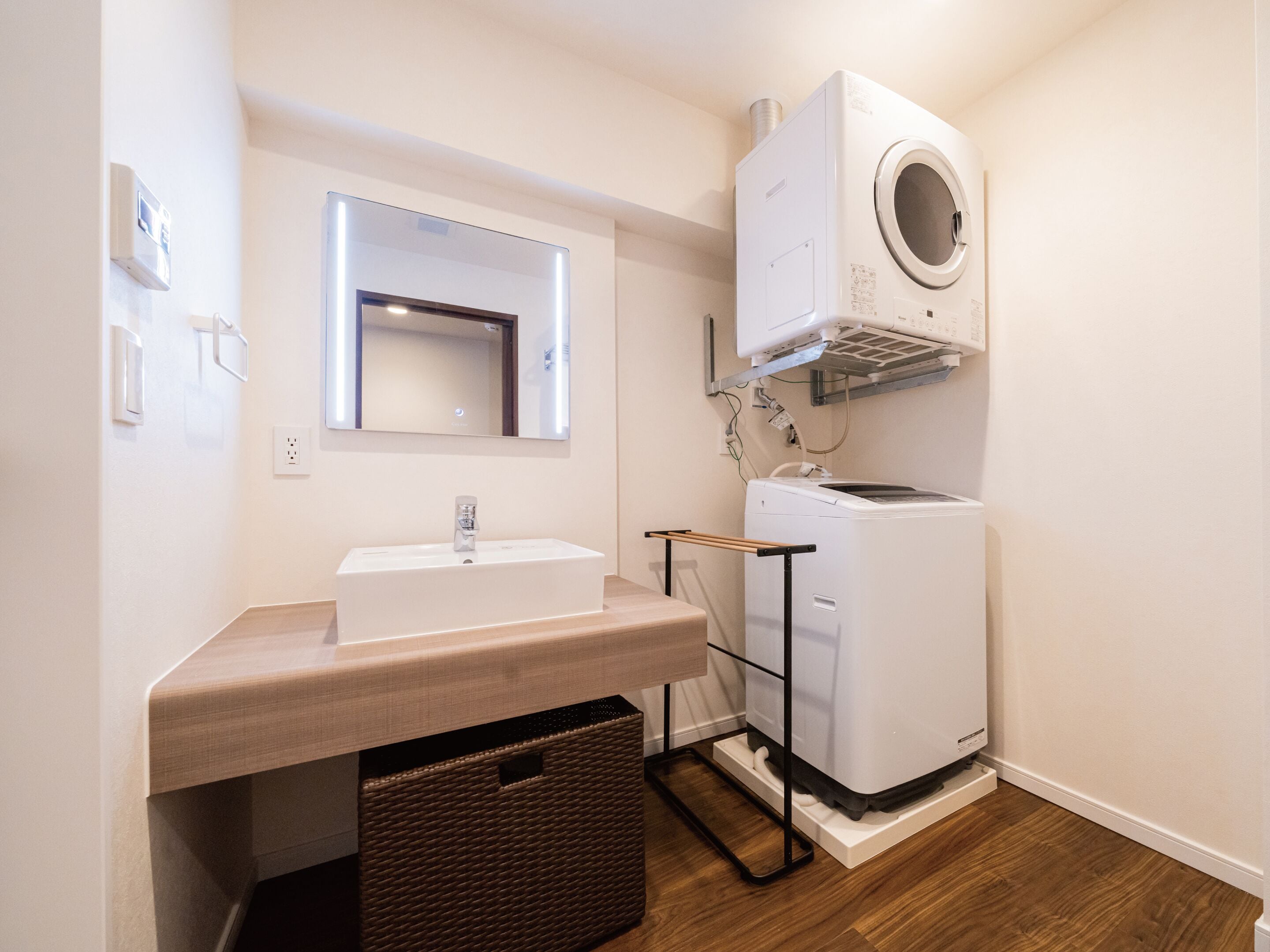 A compact bathroom with a sink, mirror, and a white washing machine.