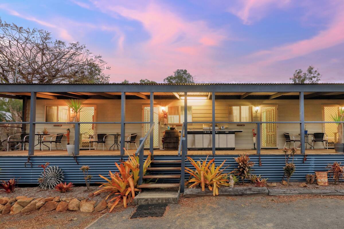 A two-story building with a covered patio area, outdoor seating, and a kitchen.