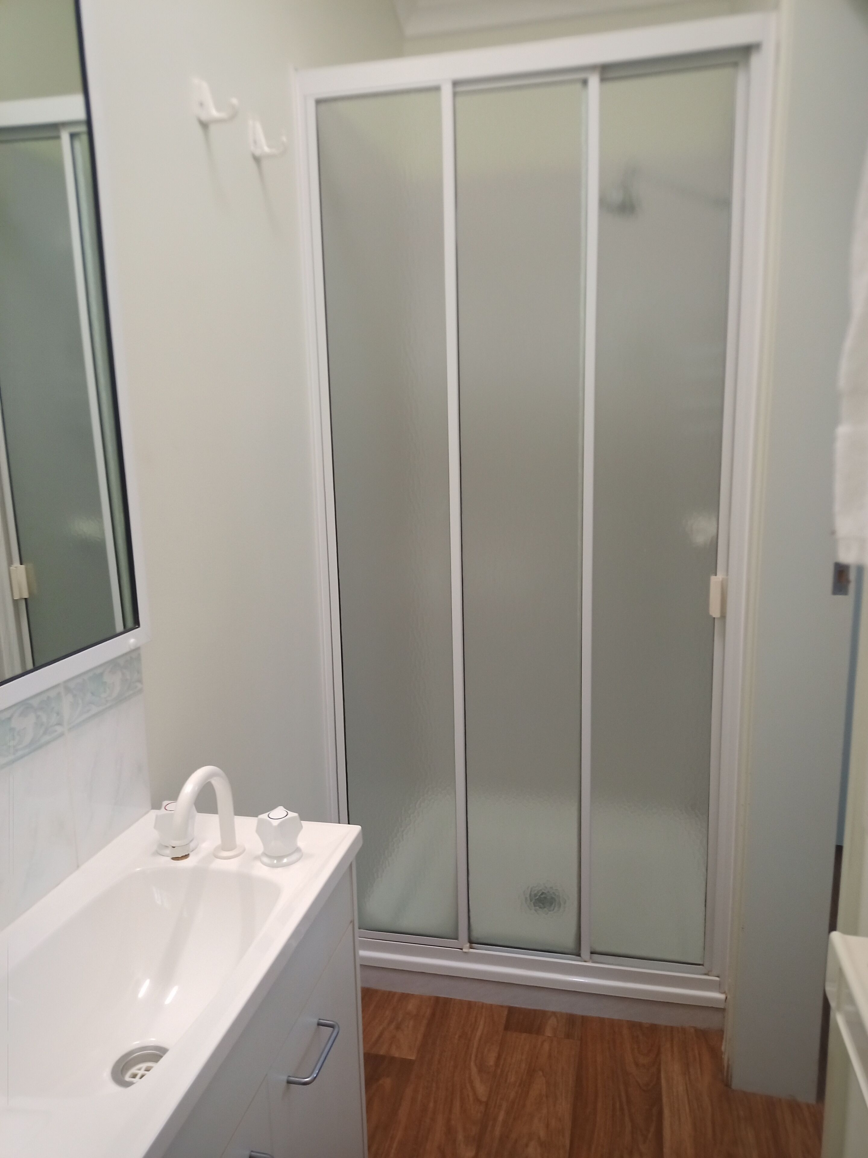 A bathroom with a white sink, a mirror, and a shower with frosted glass doors.