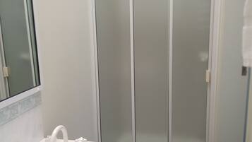 A bathroom with a white sink, a mirror, and a shower with frosted glass doors.
