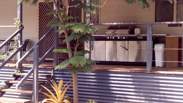 A building with a metal staircase, a small tree, and a kitchen area with cabinets and a stove.