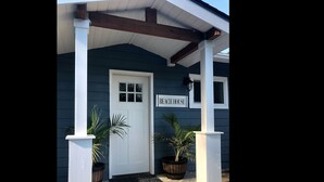 Une maison bleu foncé avec une porte blanche et une enseigne sur laquelle on peut lire « MAISON DE VACANCES AU BORD DE LA MER ».