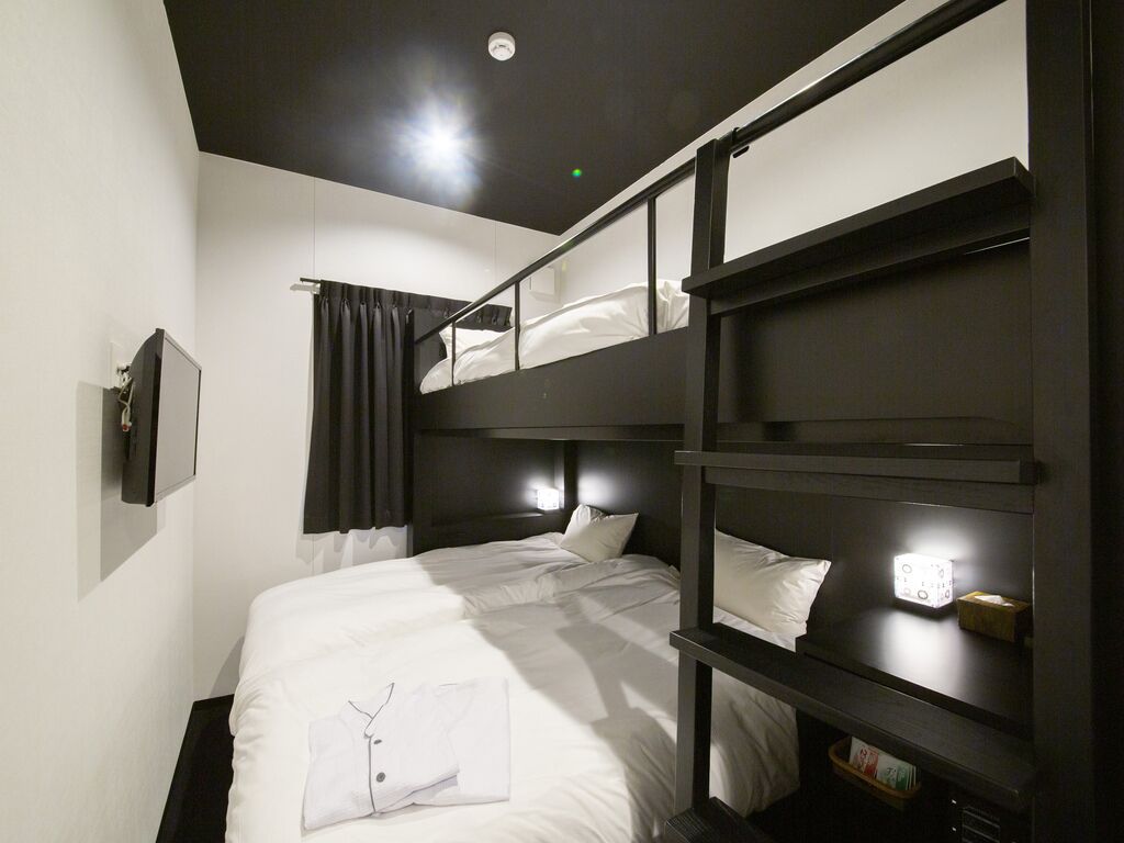 A bunk bed room with a flat-screen TV, a bedside table, and a curtain.