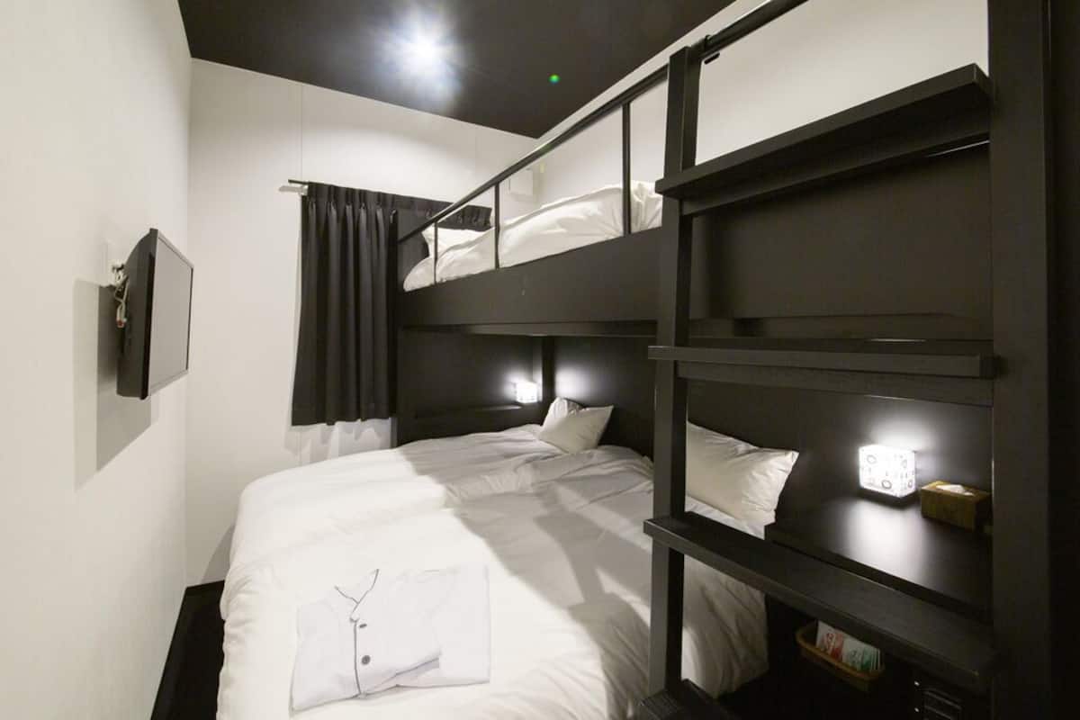 A bunk bed room with a flat-screen TV, a bedside table, and a curtain.