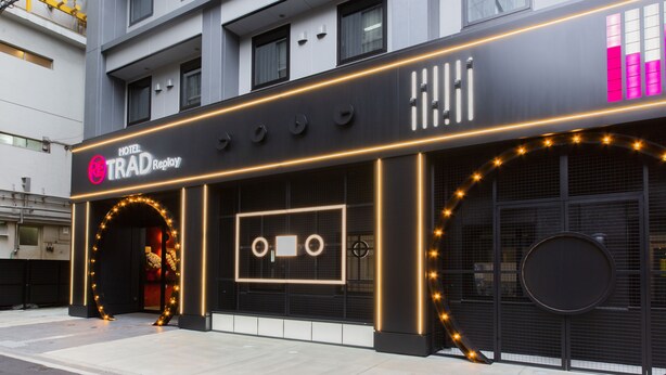 A hotel facade with a modern design, featuring a prominent entrance with a circular archway and illuminated string lights. - HOTEL TRAD Replay (Osaka)