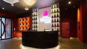 A reception area with a black reception desk, a neon sign, and a wall with geometric patterns. - HOTEL TRAD Replay (Osaka)