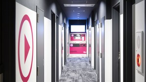 A hallway with doors on both sides, a digital display advertising a cassette sale, and a patterned carpet. - HOTEL TRAD Replay (Osaka)
