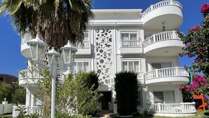 A multi-story building with balconies, a patterned walkway, and lush greenery. - Belka Golf Residence (Serik)